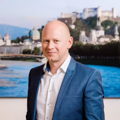 Portrait von Michael Penninger - Geschäftsführer & konzessionierter Immobilienmakler - mit einem Foto der Stadt Salzburg im Hintergrund.